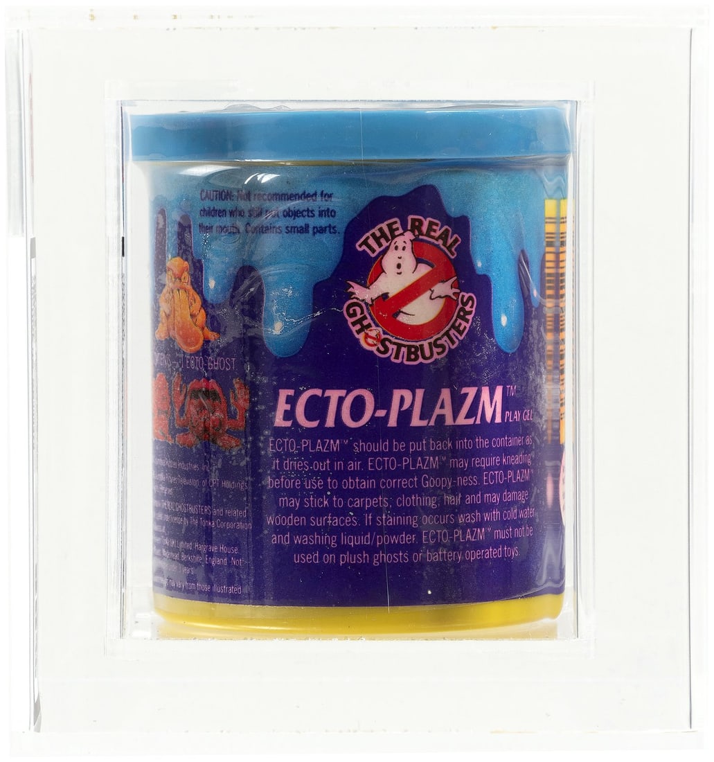 THE REAL GHOSTBUSTERS (1986) - ECTO-PLAZM SERIES 1 (BLUE) UKG 85%.: UKG graded and encapsulated container of Kenner Ecto-Plazm play gel w/one of three different Ecto-Ghost figurines. Blue Ecto-Plazm color. Some color bleed to half of container label. Mark Warner (UK)