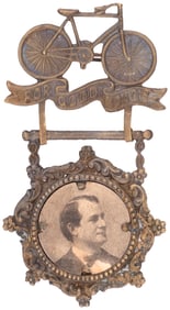 BRYAN "FOR GOOD ROADS" FIGURAL BICYCLE BRASS SHELL BADGE.