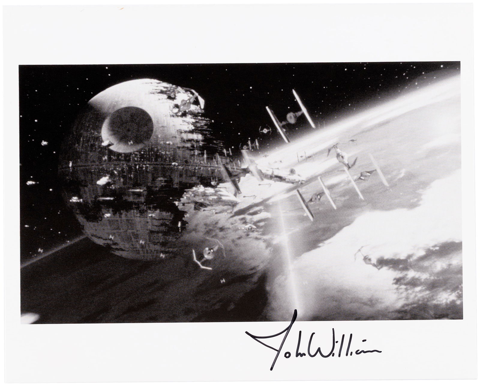 STAR WARS COMPOSER JOHN WILLIAMS SIGNED PHOTO.: 8x10" photo showing space battle in front of the second Death Star as seen in Star Wars: Return Of The Jedi. Bottom margin has been signed in black felt top pen by legendary composer John Williams, kn