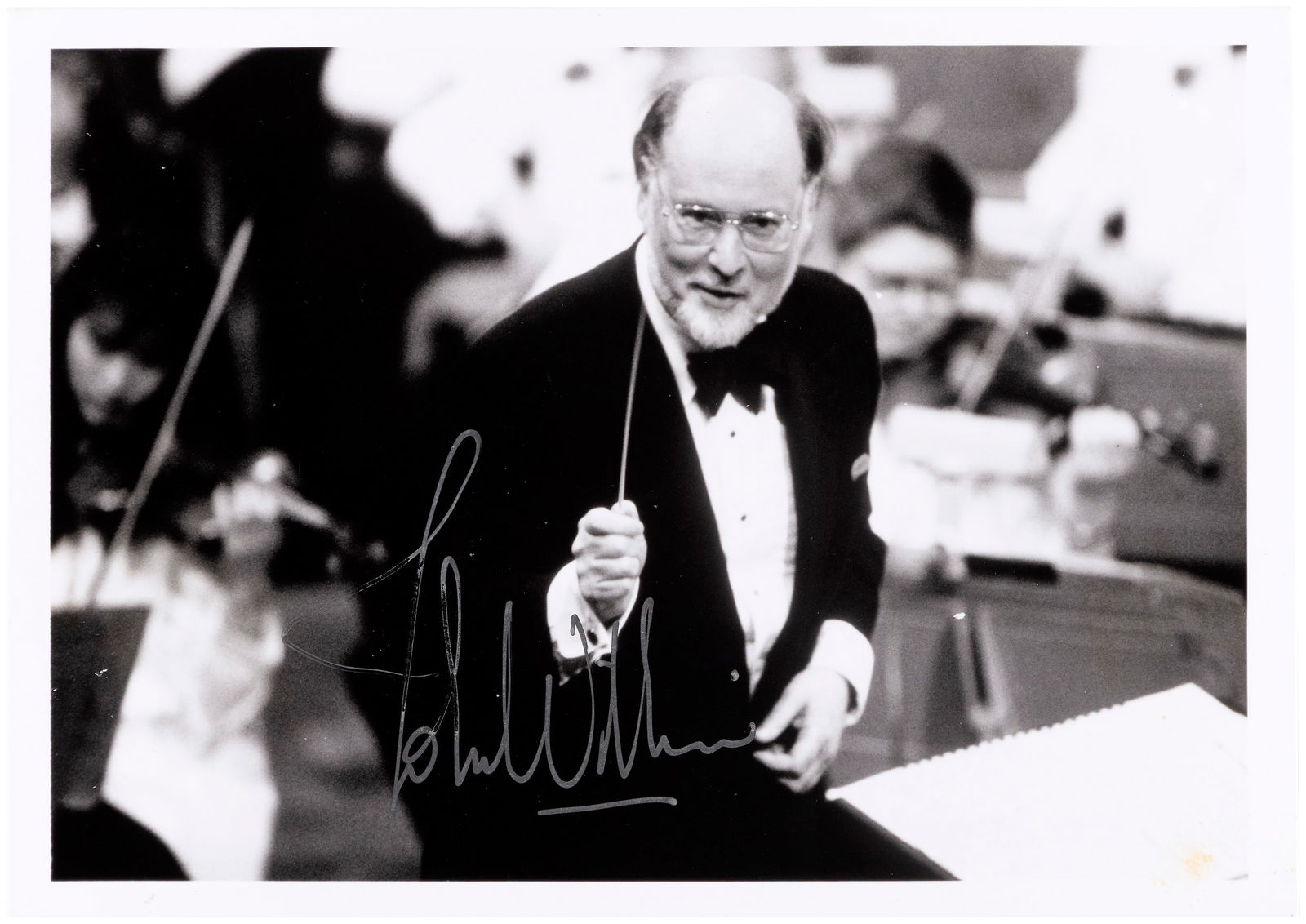STAR WARS COMPOSER JOHN WILLIAMS SIGNED PHOTO.: Glossy 5x7" photo shows legendary composer John Williams conducting. Williams, know for his Star Wars scores (as well as providing the music for films such as Jaws, Superman, Close Encounters Of The T