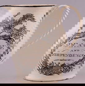 "PEACE AND INDEPENDENCE" AMERICAN REVOLUTION LIVERPOOL CREAMWARE JUG.: 7.75" tall. "Peace and Independence" slogan w/eagle, cannon, flag & shield. Frigate flying American flag reverse. Black transfer w/painted rim. Spout, rim & base chips w/stress cracks at handle joints
