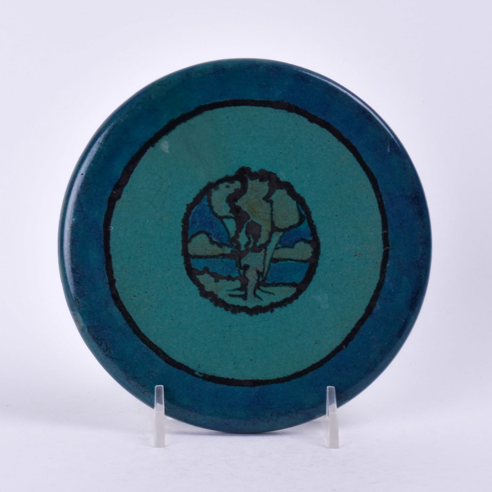 Saturday Evening Girls (Paul Revere Pottery) Tea Tile: with landscape medallion on a green and teal background. 3/8 inch high, 5 3/4 inches diameter, unmarked.