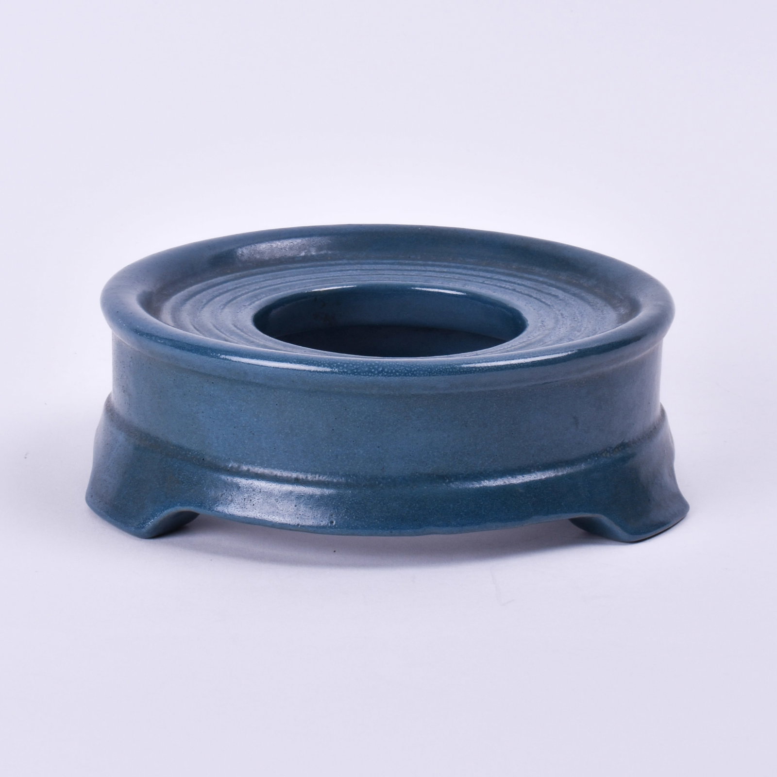 Saturday Evening Girls Vase Stand: covered in a blue glaze. 2 1/4 inch high, 7 1/8 inches wide, 7 inches deep, marked SEG/8-16/AD.