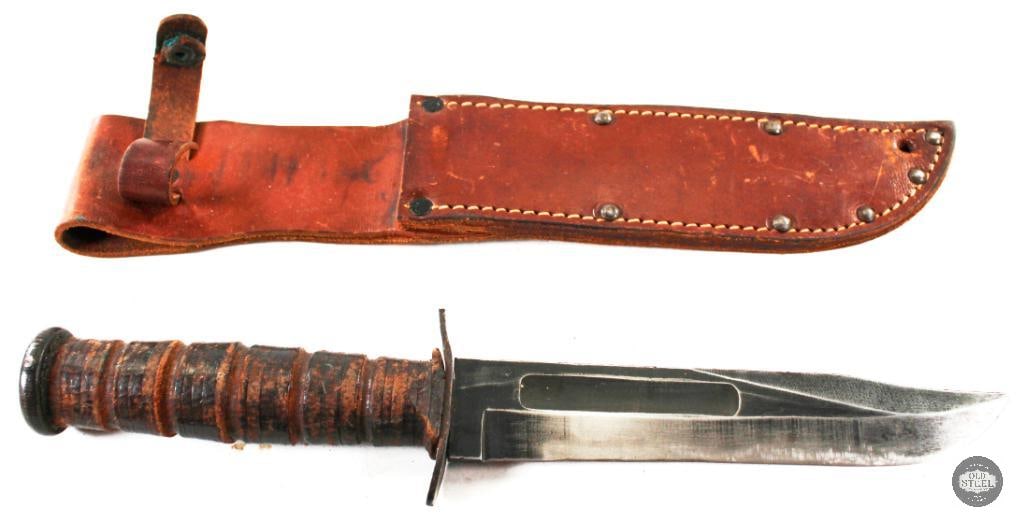 Camillus USMC KABAR and Leather Sheath: For this lot we have an original Camillus USMC KABAR and its accompanying sheath. The blade and grip show patina. The grip is stacked leather showing some dryness. The sheath is in good cond