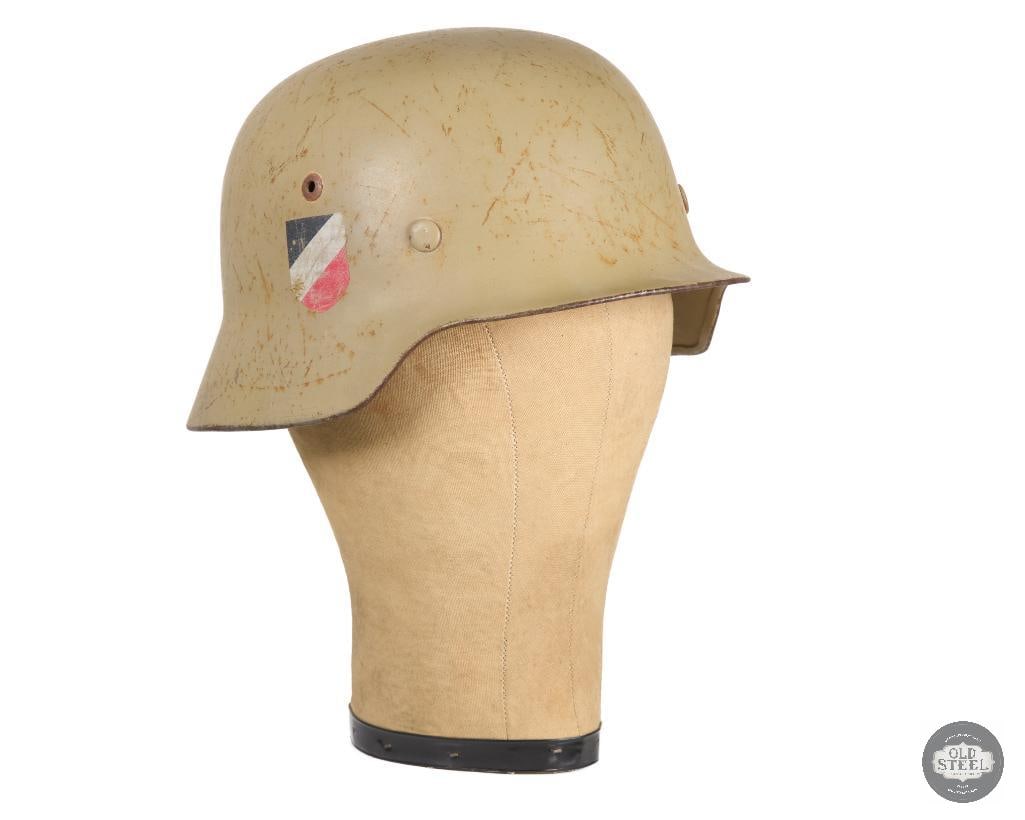M35 German WWII Double Decal Helmet: A WWII M35 double Decal helmet with tropical tan paint. Interior of the shell marked E177 and NS64. No chinstrap but the liner is in great condition with the leather being slightly dry but uncrac