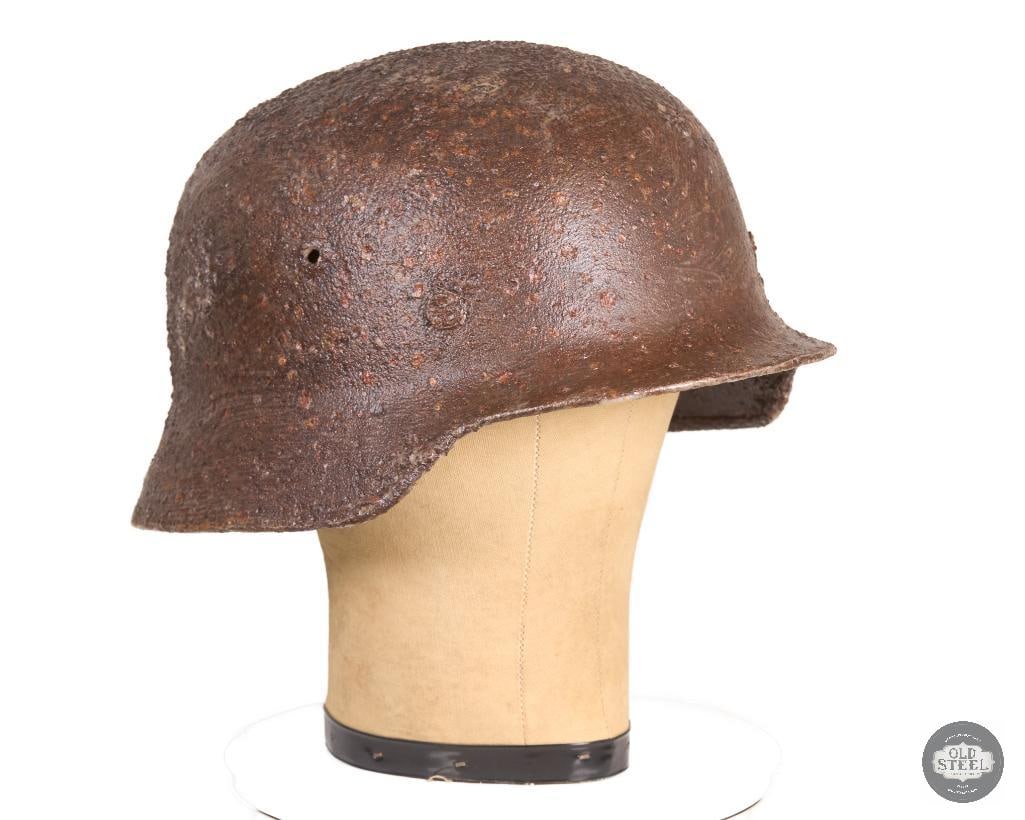 Original M40 Stahlhelm Battlefield Recovery Helmet Clear Coated Display Piece: This original M40 Stahlhelm is a battlefield recovery helmet that has been preserved with a clear protective coating to stabilize its condition. The shell exhibits heavy oxidation, corrosion, and