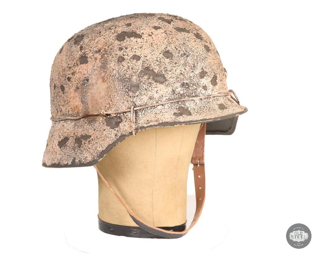 WWII German Stahlhelm M40 Original Shell w/ Snow Camo Refinish & Liner: This German M40 Stahlhelm features an original WWII steel shell that has been refinished with a modern snow camouflage paint application. The helmet includes a replacement liner installed into the