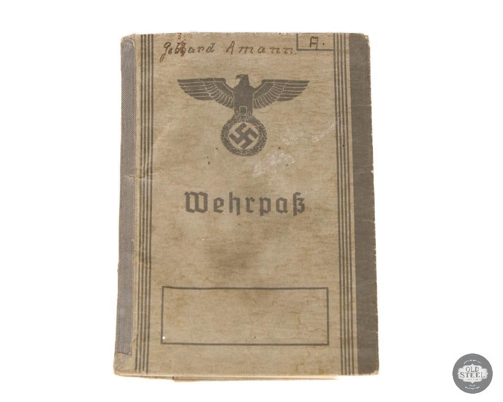 WW2 German Military Record Booklet: This item is a German WWII Wehrpass, a military record booklet issued to soldiers. It features a stylized eagle and swastika emblem on the front cover, known as the Reichsadler. These booklets