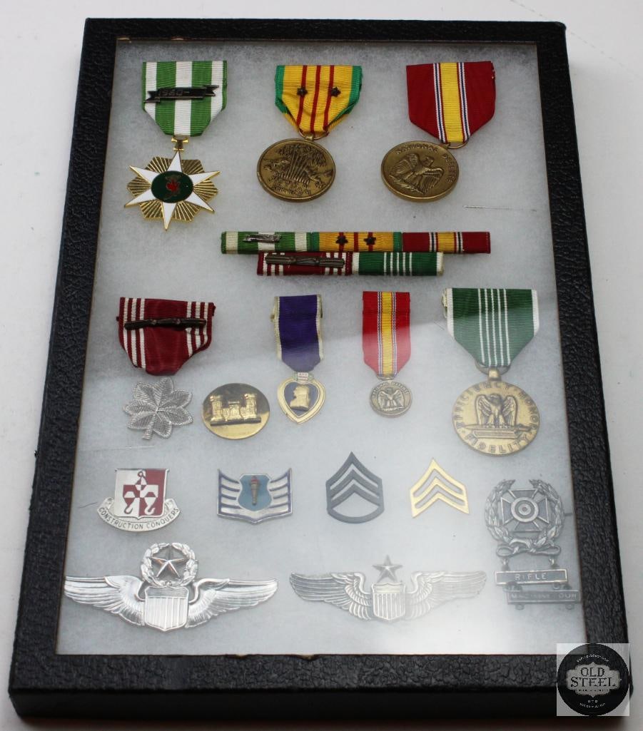 Collection of U.S. Military Medals and Pins: This is a framed collection of U.S. Military Medals and Pins , potentially from the WWII era. The display includes various medals with colorful ribbons, small pins, and possibly a commemorative shadow
