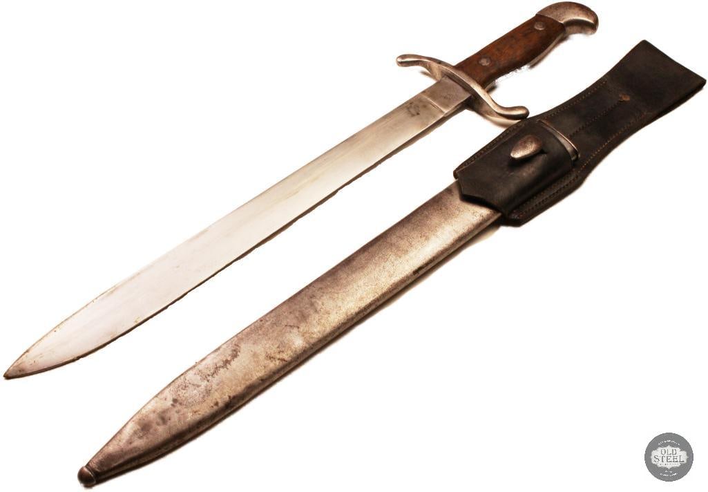 Original Argentine Artillery Bolo Knife w/ Scabbard & Frog Crest & Engraving: Original Argentine artillery bolo knife featuring an engraved blade with crest and decorative markings. The knife is paired with its scabbard and frog, completing the set. The blade shows age-related
