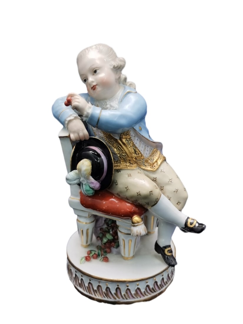 MEISSEN PORCELAIN FIGURE OF A NOBLE BOY, GERMANY, 19TH CENTURY: Meissen porcelain figure of a noble boy, Germany, 19th century. The boy is seated on a chair with a tasseled cushion and dressed in 18th-century aristocratic costume, including lace-trimmed shirt, sto