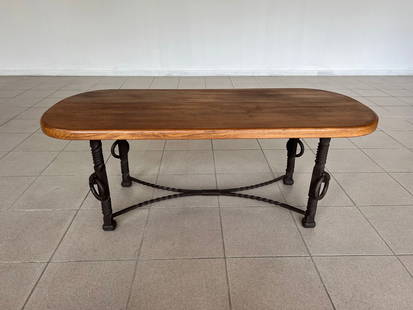 FRENCH COUNTRY WROUGHT IRON COFFEE TABLE: Dimensions: H 18.3” x W 47.5” x D 21.2”. French Mid Century Modern coffee table with wrought iron base and solid oak oval top. Ring iron elements on each side of the base. 042