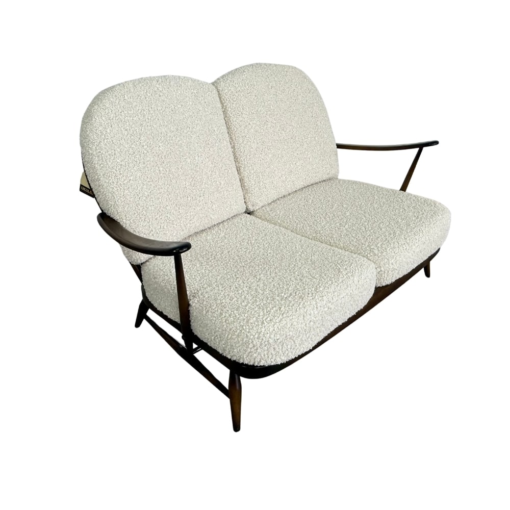 ERCOL WINDSOR TWO-SEAT SOFA: Dimensions: H 33.5” x W 53” x D 39” x SH 14.5”. Two-seat “Windsor” sofa by Ercol, newly upholstered in off-white boucle, 1970s. Rare last edition with tag