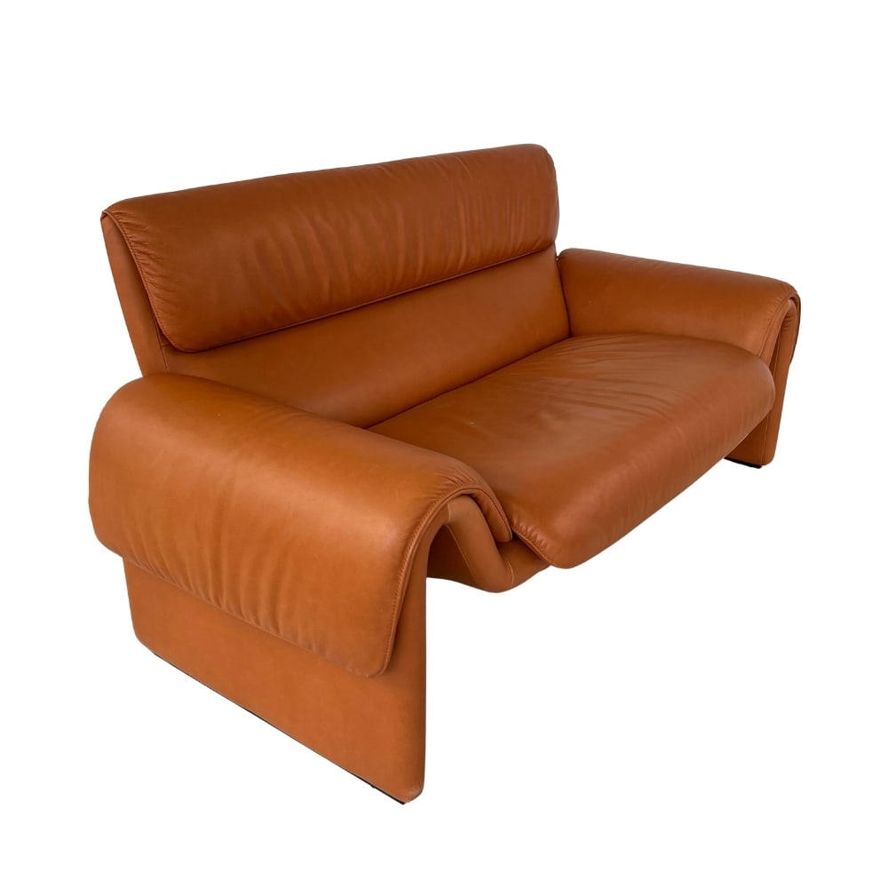 DE SEDE DS 2011 BROWN LEATHER SOFA: Dimensions: H 32” x W 64” x SD 23” x SH 16.5”. Brown leather two-seater sofa DS 2011 from De Sede with folded armrests.