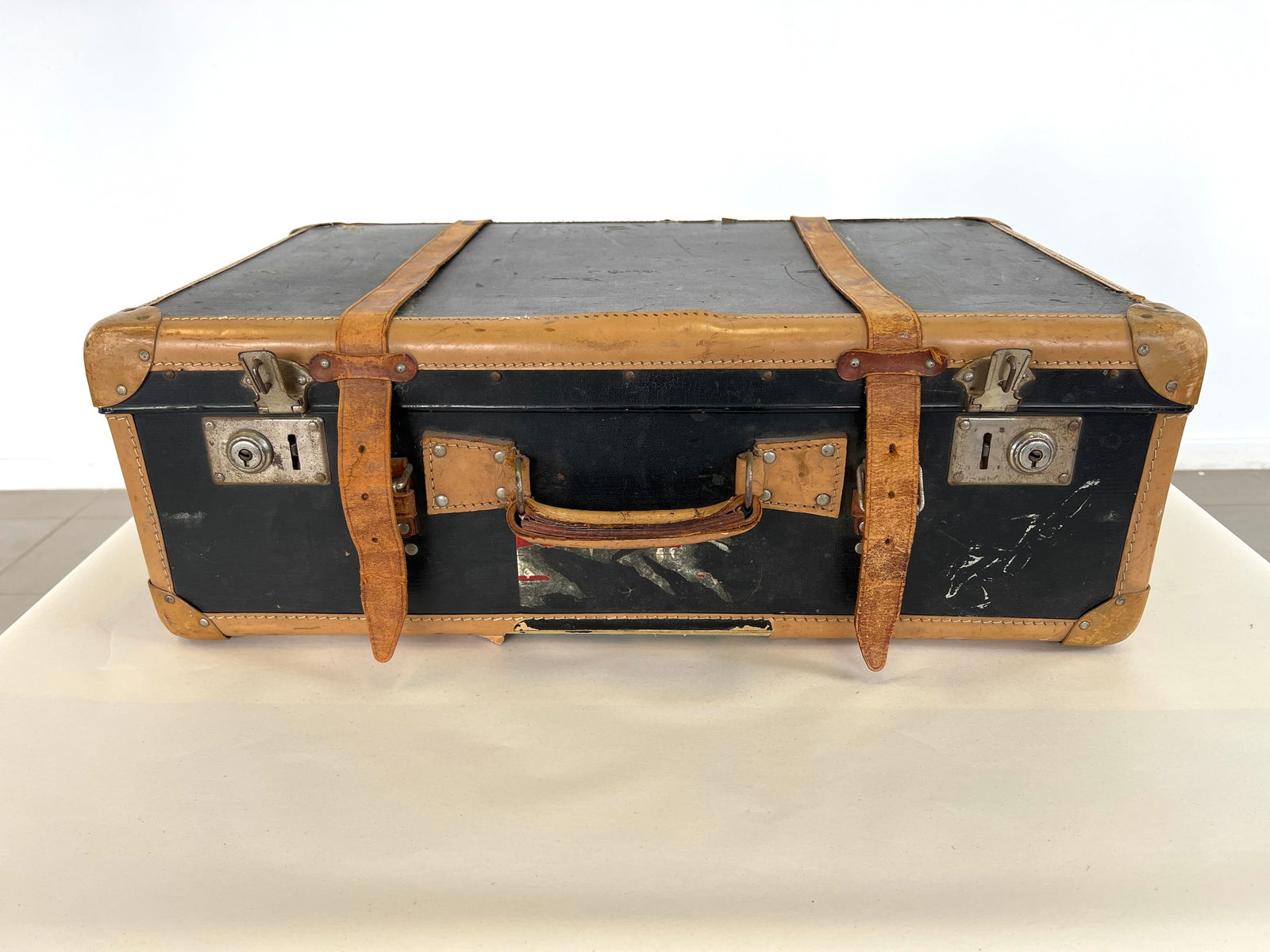 ANTIQUE K. V. HOVEN BERN LEATHER SUITCASE: Dimensions: H 9” x W 25.5” x D 15”. Antique K.V. Hoven Bern black and brown leather suitcase.