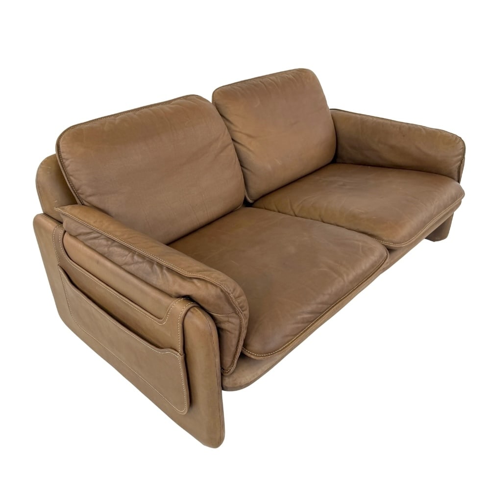 DE SEDE DS61 LEATHER TWO-SEAT SOFA, 1960s: Dimensions: H 27.5” x W 56.5” x D 34” x SH 15". De Sede DS61 brown leather two-seat sofa with magazine rack and removable cushions.