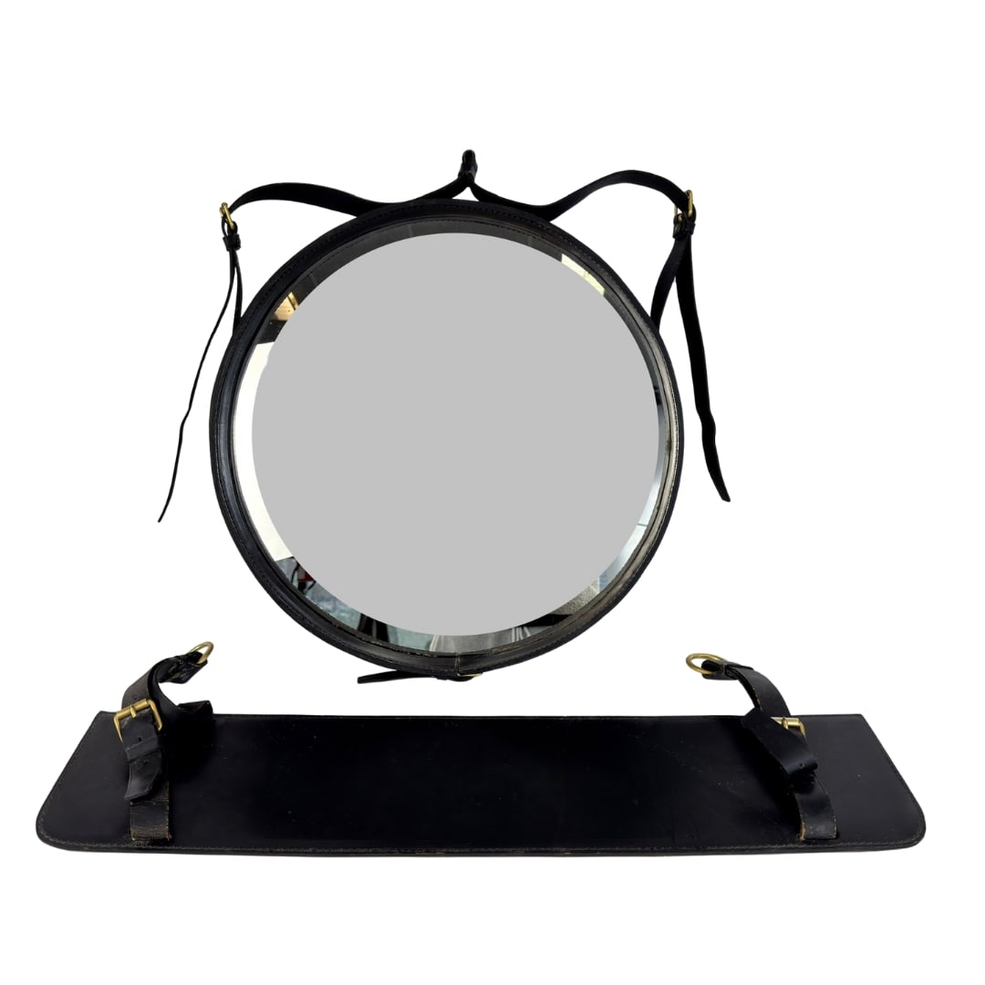 LEATHER MIRROR BY JACQUES ADNET: Dimensions: Diam. 18” x D 3”. Vintage stitched black leather wall mirror with wall-mounted leather organizer by Jacques Adnet. Dimensions: (organizer) H 6.7” x W 28”.