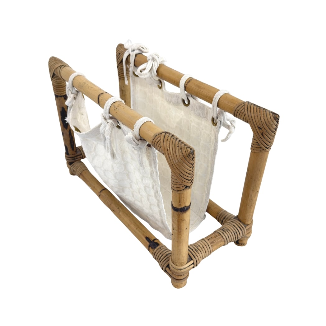 BAMBOO AND RATTAN MAGAZINE RACK: Dimensions: H 13.3” x W 20” x D 8.5”. Vintage bamboo and rattan magazine rack with white fabric sling.