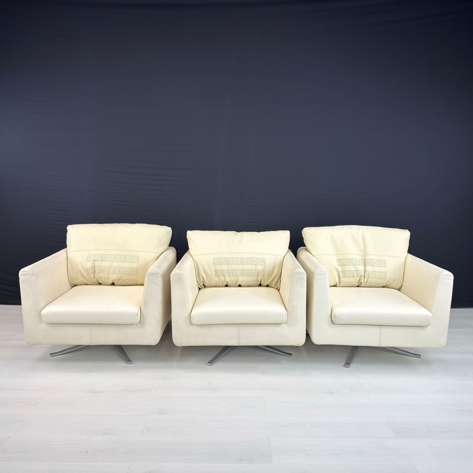 (3) KNOLL LEATHER ARMCHAIRS: Dimensions: H 26.5” x W 34” x D 34” x SH 16”. Set of 3 of armchairs by Walter Knoll in cream leather with aluminum base. Dimensions: H with pillows 33.5".