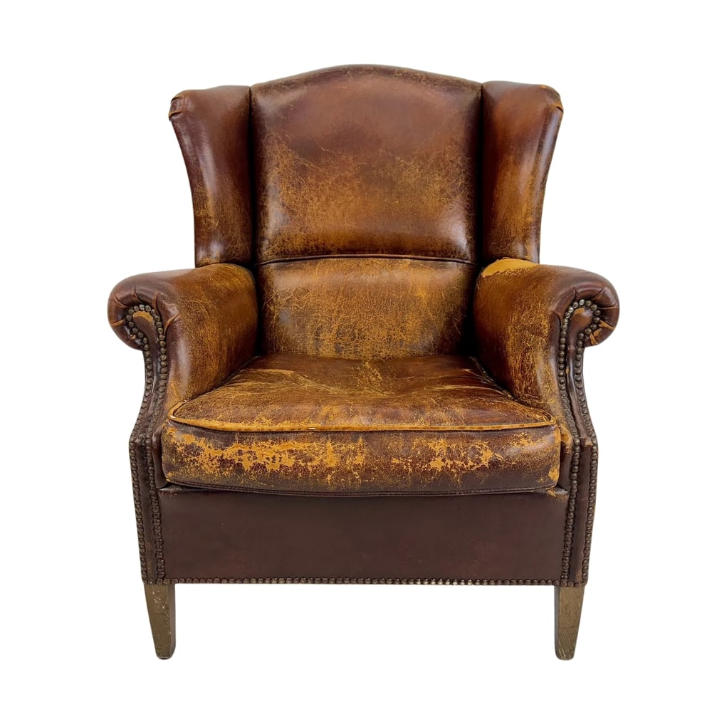 VINTAGE LEATHER WINGBACK CHAIR: Dimensions: H 40” x W 32” x D 37.5” x SH 16.7”. Vintage Danish wingback chair in hand-patinated sheepskin leather finished with decorative nails.