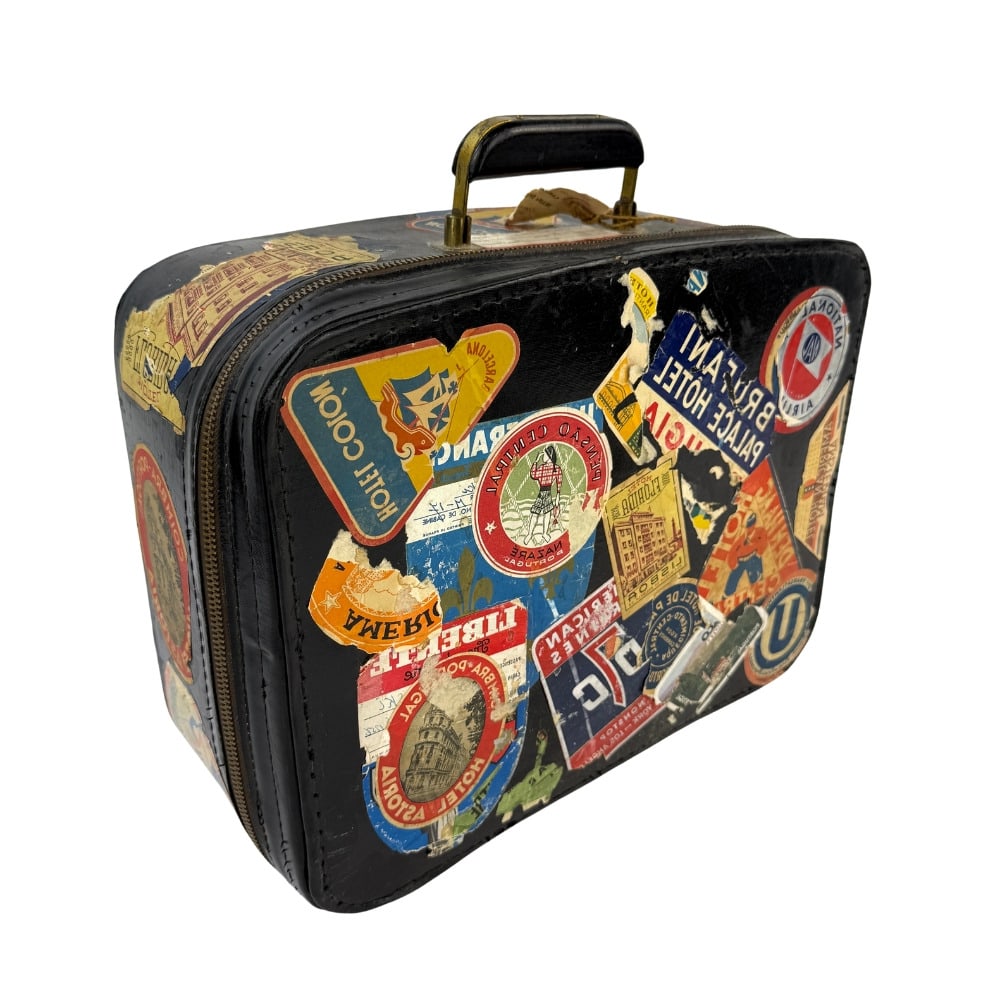 VINTAGE BLACK SUITCASE: Dimensions: 11.5” x W 14.7” x D 6.7”. Vintage black suitcase covered in travel stickers.