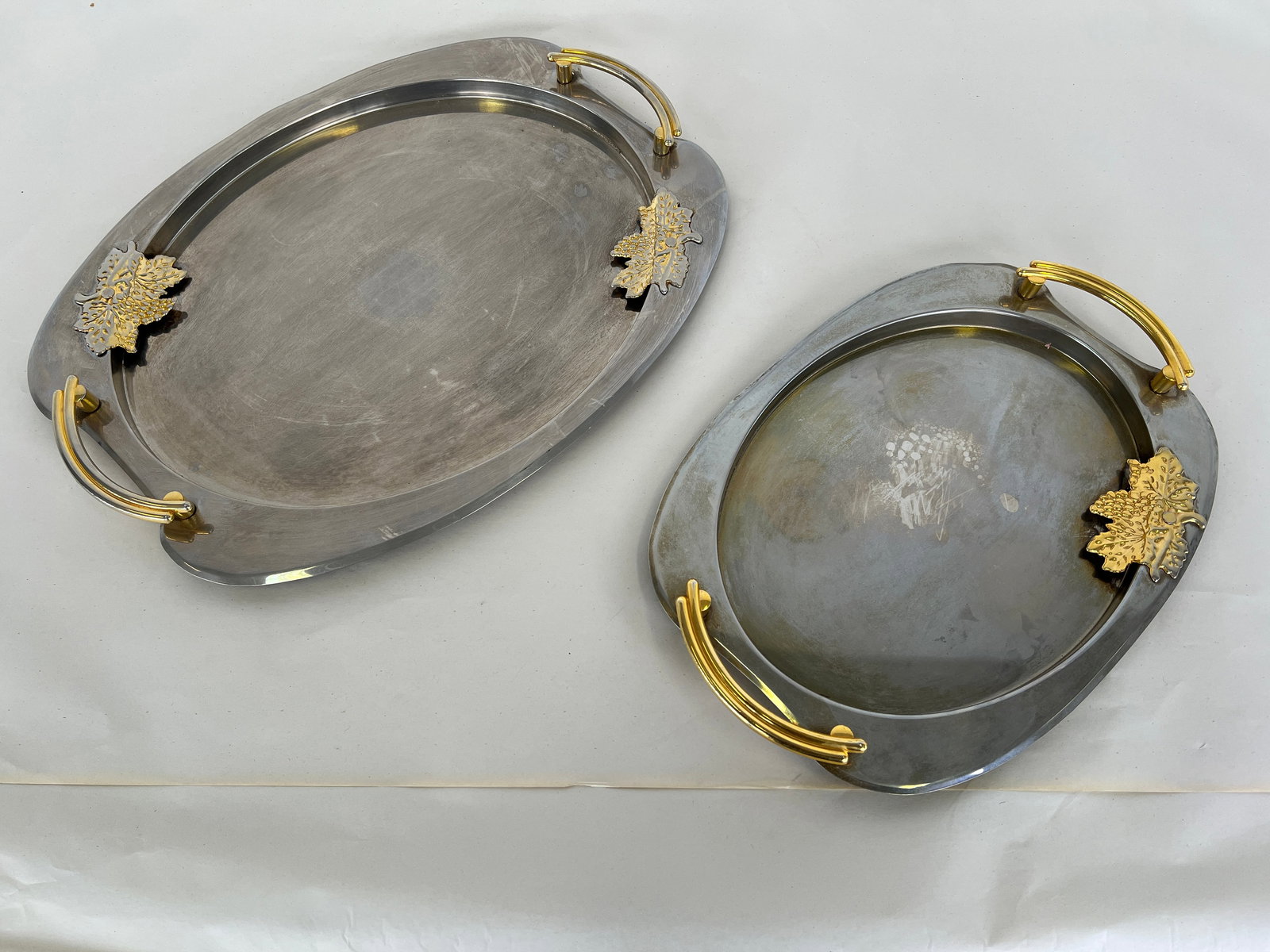 (2) VINTAGE FRENCH SERVING TRAYS: Dimensions: W 17 x D 11.7”. Set of 2 French oval metal serving trays with handles. Dimensions: W 20.7" x D 15.7".