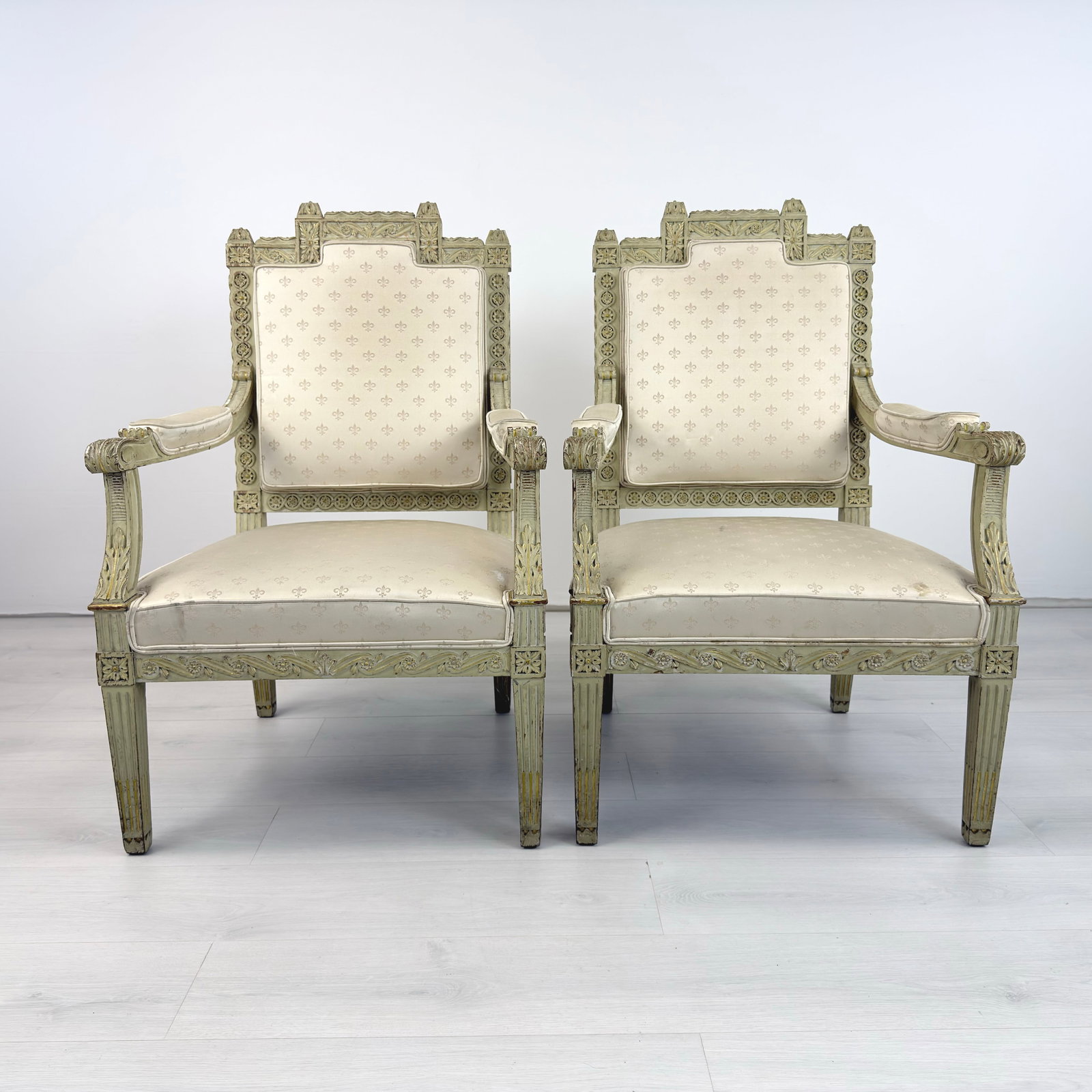 LOUIS XVI STYLE ARMCHAIRS, A PAIR: Dimensions: H 39.7” x W 26” x SD 21” x SH 17”. Pair of Antique Louis XVI style hand painted carved wood armchairs with original white fleur-de-lys patterned upholstery.