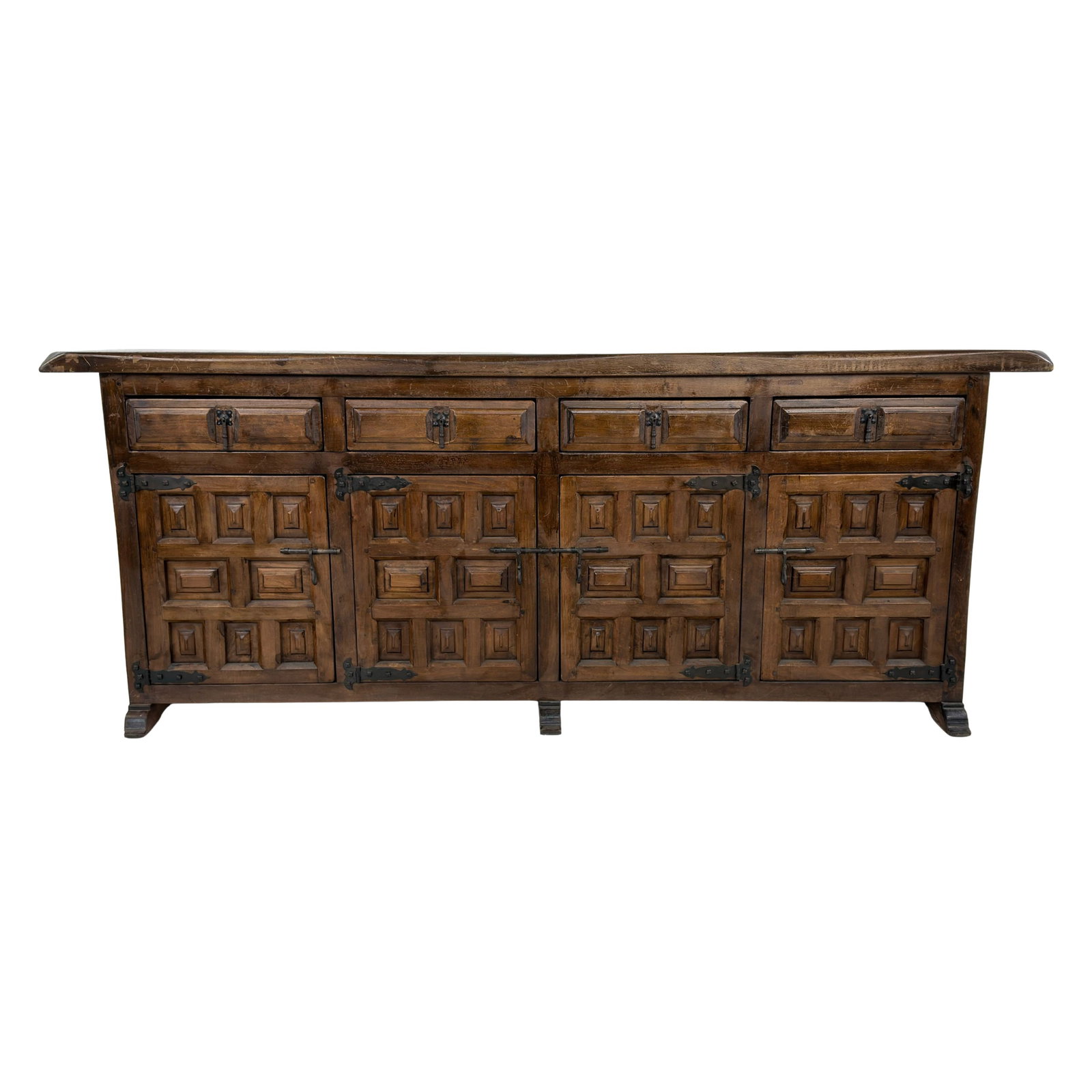 SPANISH BRUTALIST SIDEBOARD: Dimensions: H 31.5” x W 79” x D 15.5”. Vintage Spanish Brutalist carved sideboard with 4 drawers, 4 cupboards and wrought iron hardware.