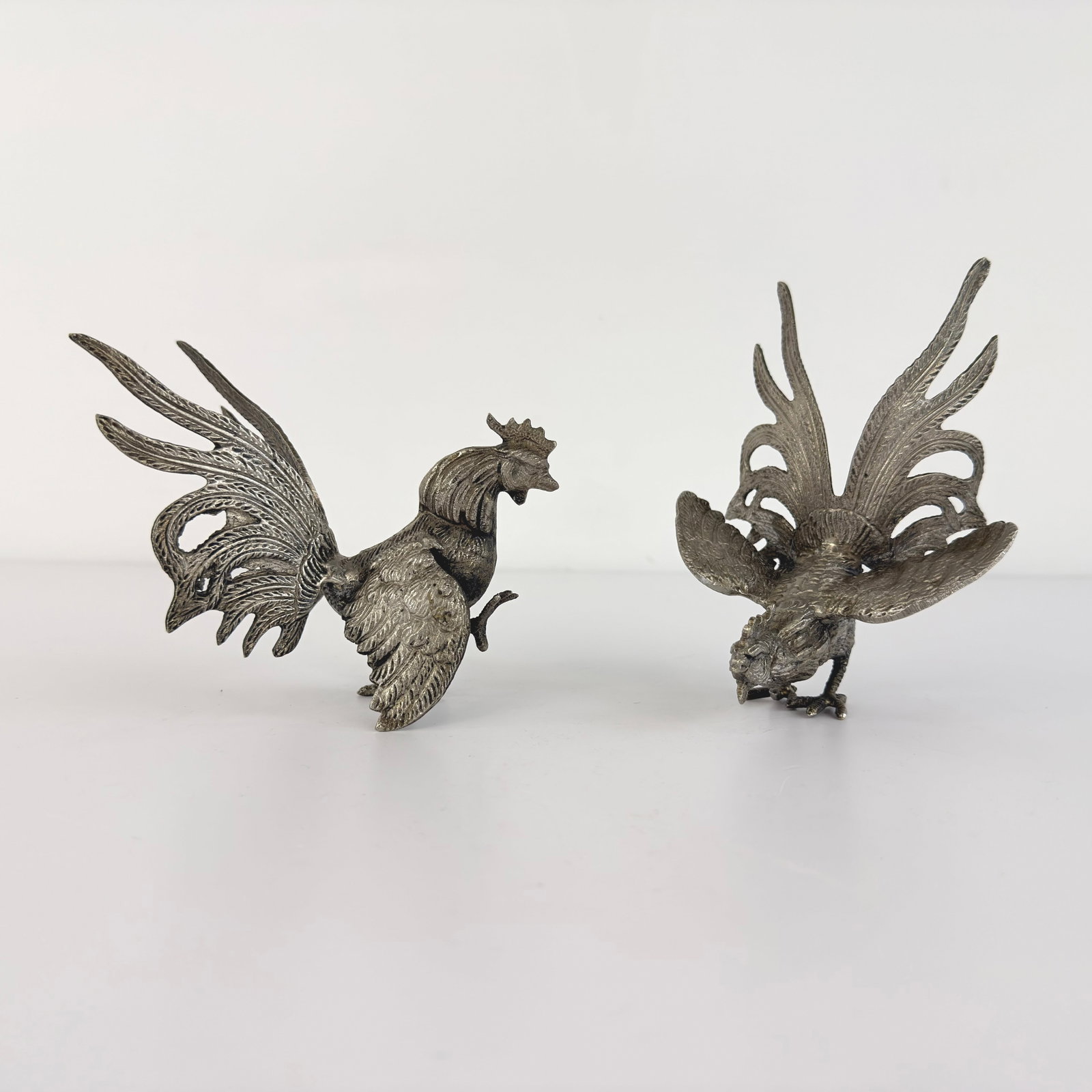 VINTAGE SILVER PLATED ROOSTERS, A PAIR: Dimensions: H 5.7” x W 4.5”. Pair of Vintage silver plated fighting roosters, 1960s.
