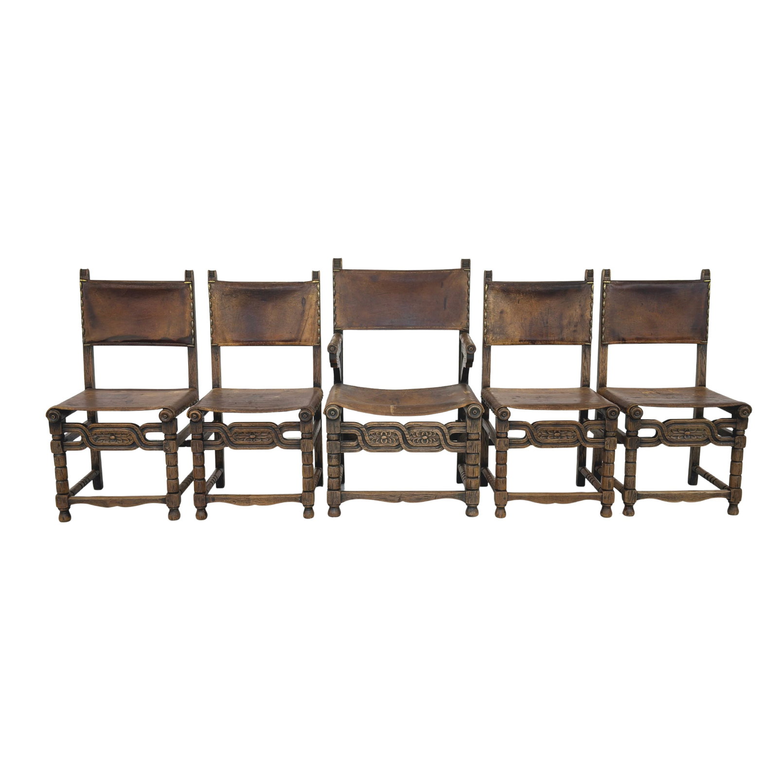 (5) SPANISH LEATHER BRUTALIST CHAIRS: Dimensions: H 39.5” x W 18.5” x D 16.5” x SH 18.5”. Set of 5 Spanish Brutalist carved wood chairs with original brown leather seats and backs. One of the chairs is with armrest