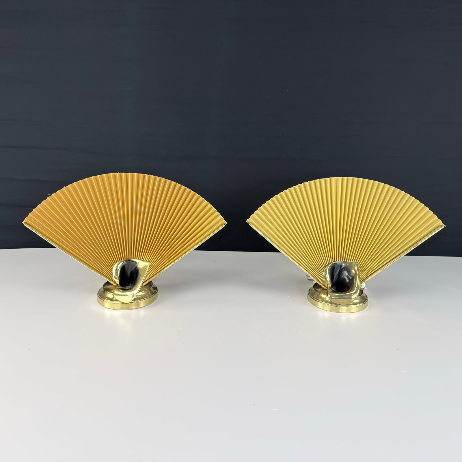HOLLYWOOD REGENCY FAN TABLE LAMPS, A PAIR: Dimensions: H 11.5” x W 17.5”. Pair of Hollywood Regency style accordion fan table lamps with mustard yellow fabric shades and polished brass base.