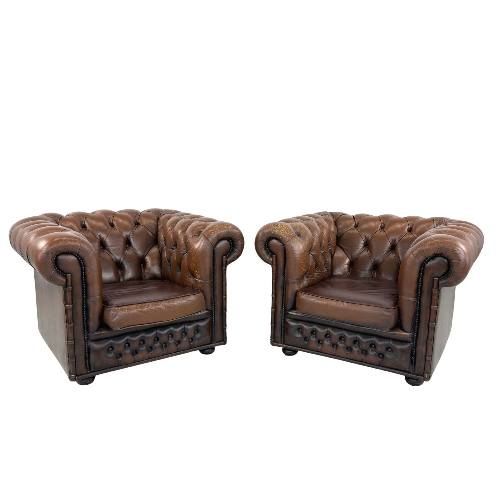 CHESTERFIELD CLUB CHAIRS, A PAIR: Dimensions: H 31” x W 42.5” x D 41” x SH 17”. Pair of Vintage buttoned brown leather Chesterfield club chairs with loose padded cushions.