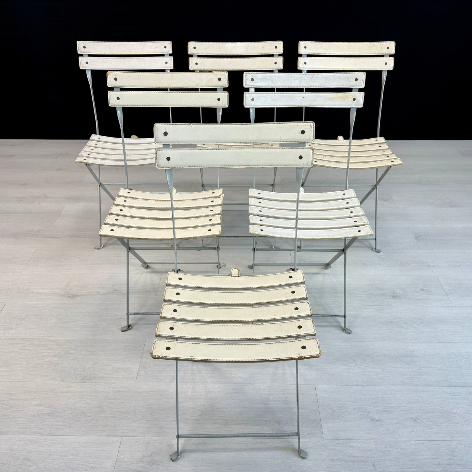 (6) CELESTINA FOLDING CHAIRS BY MARCO ZANUSO, 1970s: Dimensions: H 32” x W 15” x D 20” x SH 18”. Set of 6 white leather folding chairs by Marco Zanuso for Zanotta. Metal base painted in grey. Manufactured in 1970s.