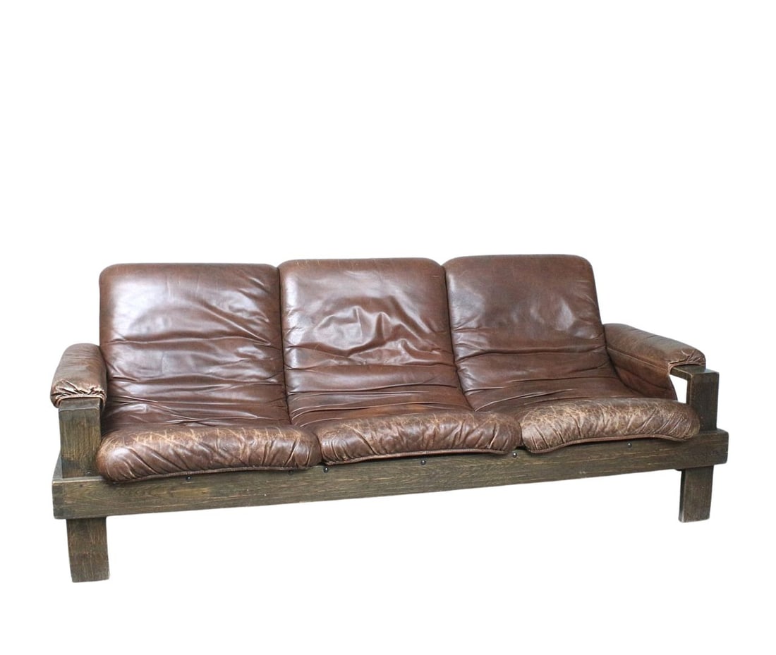 BRUTALIST SOFA MANNER OF ESKO PAJAMIES, 1970s: Dimensions: H 31.4” x W 82.6” x D 37.4” x SH 17.3”. Vintage Brutalist three-seater sofa manner of Esko Pajamies with brown leather cushions attached with leather straps and