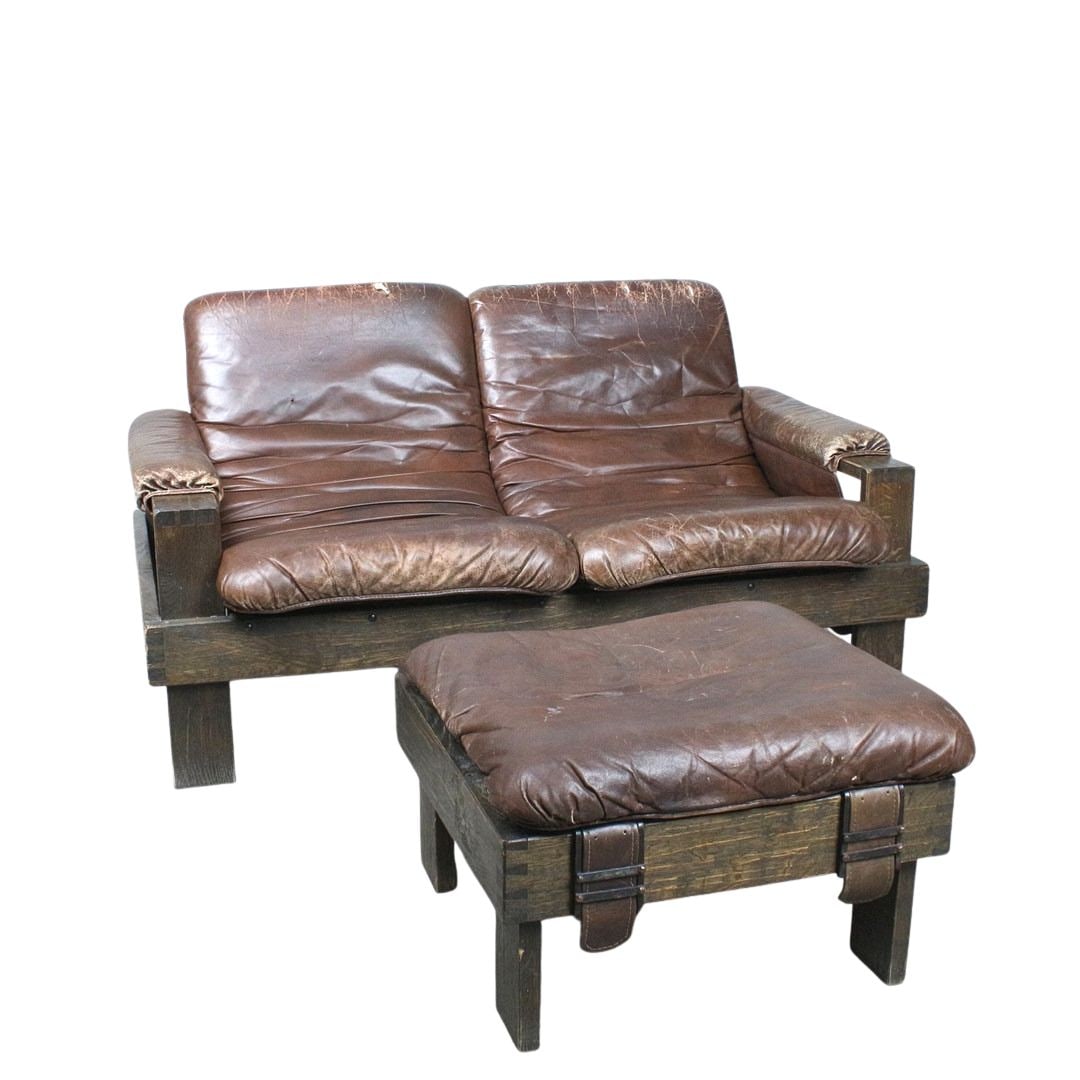 BRUTALIST SOFA WITH OTTOMAN MANNER OF ESKO PAJAMIES, 1970s: Dimensions: H 32” x W 59” x D 37.5” x SH 17.3”. Vintage Brutalist two-seater sofa manner of Esko Pajamies with matching ottoman in brown leather with loose padded cushions