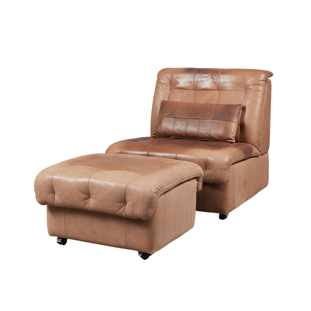 SWISS LOUNGE CHAIR WITH OTTOMAN, 1970s: Dimensions: H 32.6” x W 34.2” x D 33.4” x SH 15.7”. Vintage Swiss lounge chair with ottoman and a pillow in brown leather. Dimensions: (ottoman) H 15.7” x W 26.3”