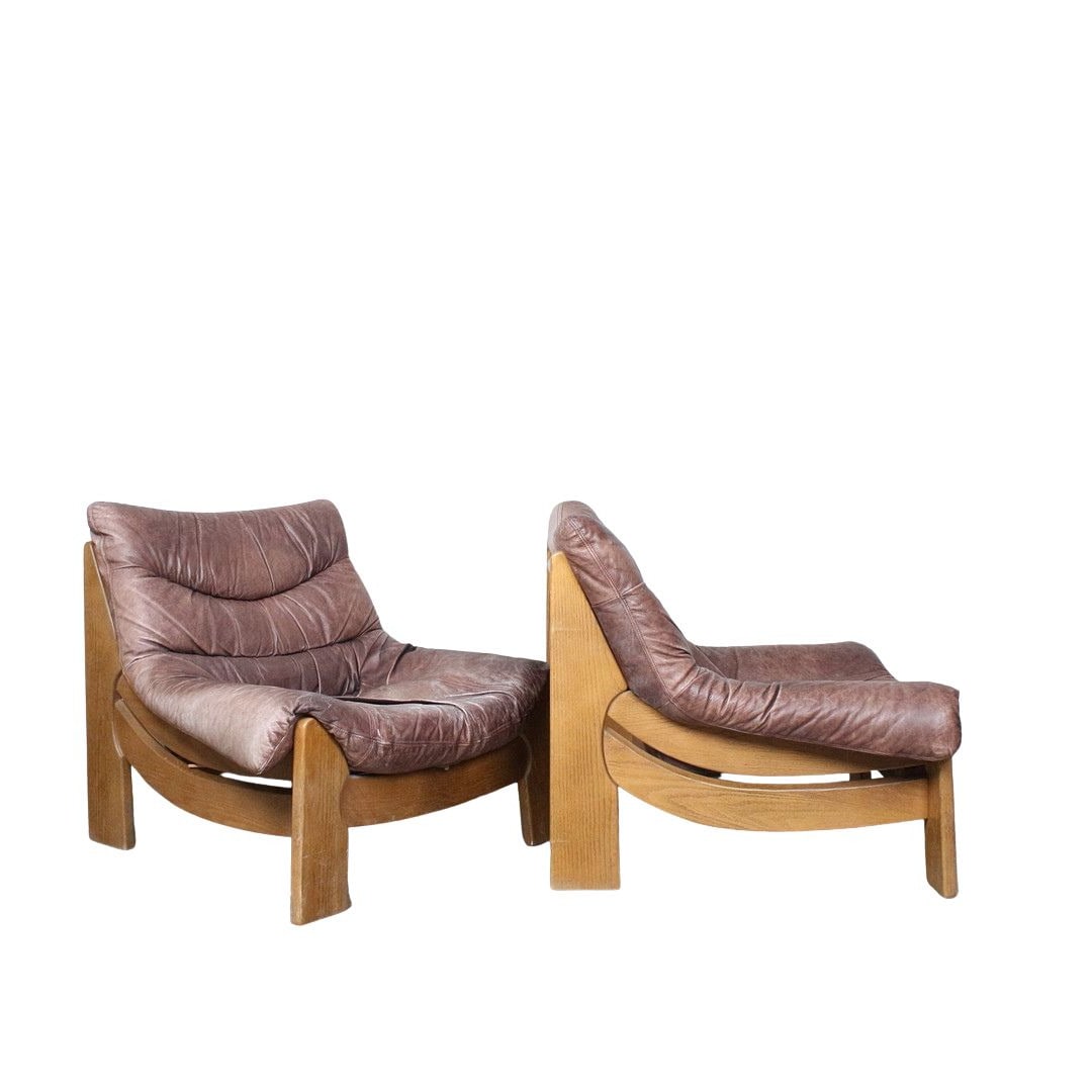 LOUNGE CHAIRS BY MAISON REGAIN, A PAIR: Dimensions: H 31.8” x W 37” x D 35.4” x SH 14.1”. Pair of French Brutalist oak lounge chairs by Maison Regain with light brown leather cushions, 1960s.