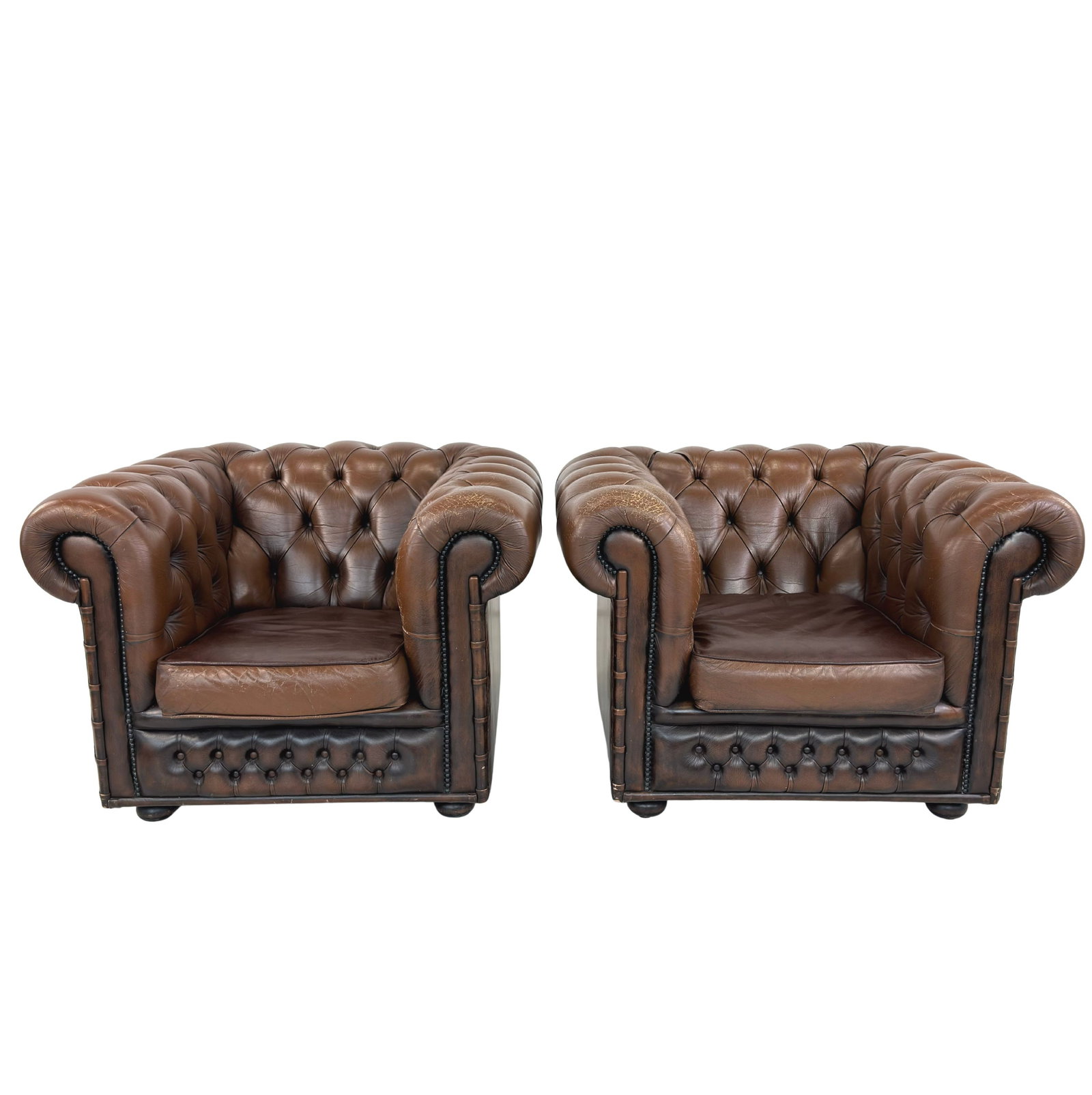 CHESTERFIELD CLUB CHAIRS, A PAIR: Dimensions: H 31” x W 42.5” x D 41” x SH 17”. Pair of Vintage buttoned brown leather Chesterfield club chairs with loose padded cushions.
