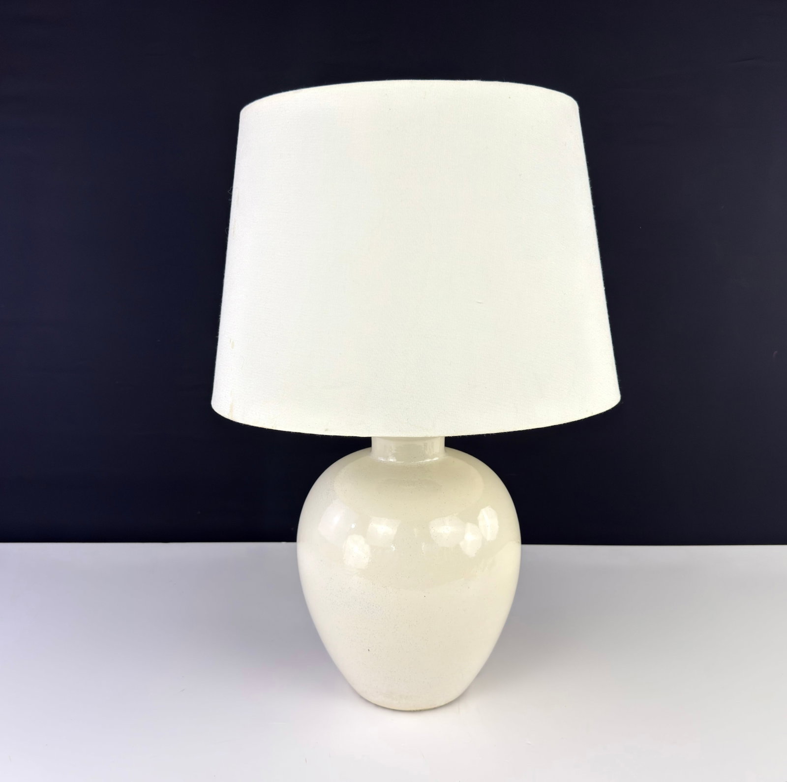 VINTAGE SIGNED TABLE LAMP: Dimensions: H 18” x W 9”. Vintage ceramic table lamp with off-white fabric lampshade. Signed. Dimensions are for the base.