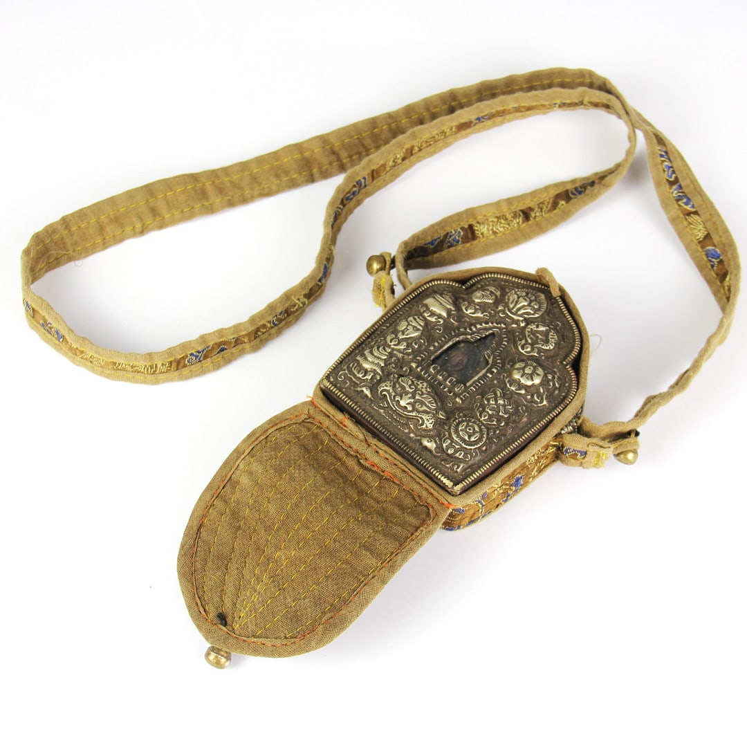 A Tibetan copper and white Ga'u prayer box with a silk carrying case and painted clay de (1 of 2)