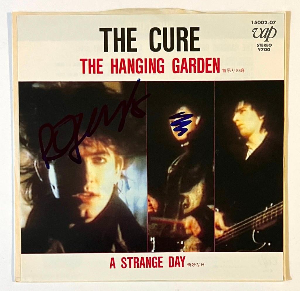 The Cure: Robert Smith In-Person Signed "The Hanging Garden" 45 RPM Record (Beckett/BAS COA): "The Hanging Garden" Japanese 45 record signed on the cover flat in blue felt tip marker by Robert Smith, who's penned over one of the band member's faces. In fine condition. Record is included.