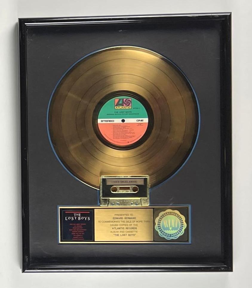 “The Lost Boys” Gold Sales Award Presented to Ed Germano: This is an RIAA Certified Gold Sales Award presented to Edward Germano to commemorate the sale of more than 500,000 copies of the *The Lost Boys* soundtrack. Measuring approximately 17 x 21 inches, th