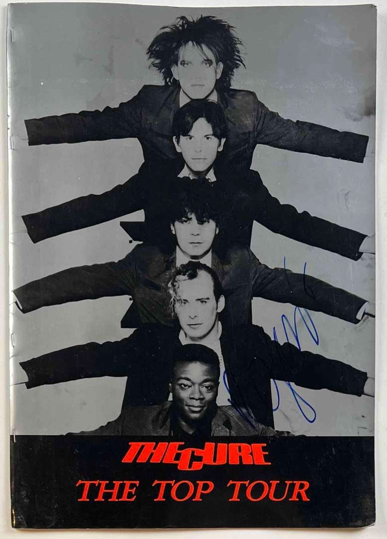 The Cure: Robert Smith In-Person Signed "The Top Tour" Program (Beckett/BAS Authentication): Original tour program from The Cure’s 1984 “The Top Tour,” boldly signed on the front cover in blue felt tip by iconic front man Robert Smith. The striking black-and-silver cover fea