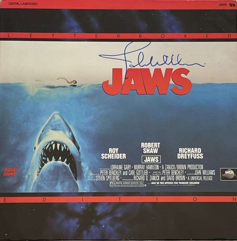 Jaws: John Williams Signed "Jaws" Laserdisc (Third Party Guaranteed): Signed laserdisc cover for the film "Jaws," autographed in blue felt tip marker by composer John Williams. The cover measures approximately 12" x 12". No disc included. In fine condition with minor ed
