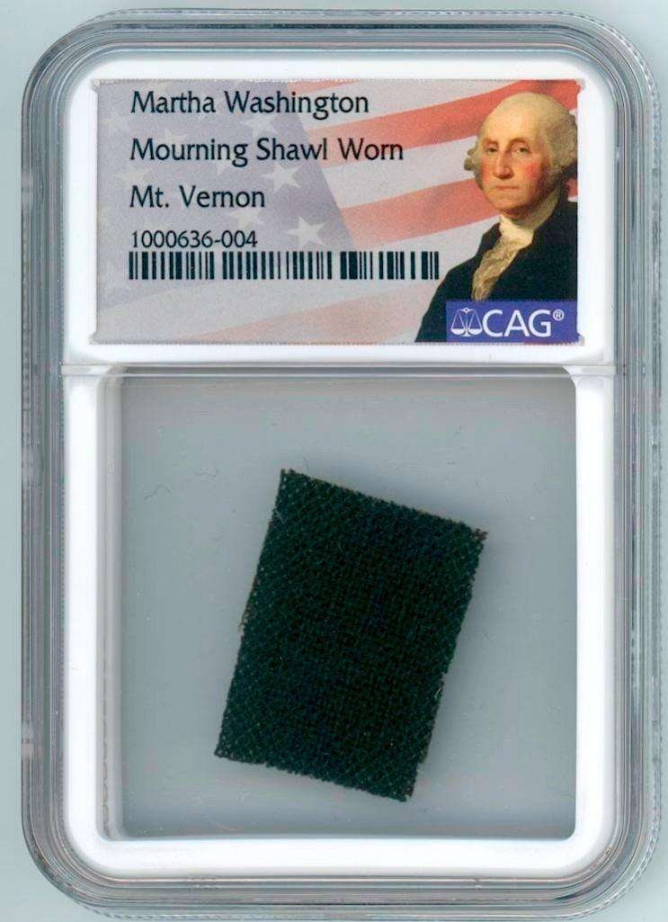 Martha Washington Mourning Shawl Swatch Worn at George Washington's Funeral (CAG): Rare swatch of black mourning shawl fabric worn by Martha Washington at the 1799 funeral of General George Washington. The approximately 1" x .75" swatch is professionally encased in a 3.25" x 2.25" C