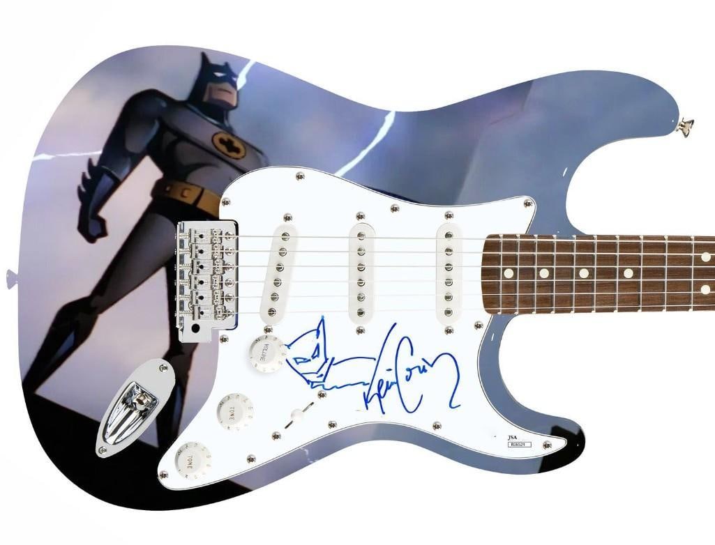 Batman Custom Graphics Kevin Conroy Signed Stratocaster-Style Guitar (JSA Authentication): Batman graphics custom signature edition Stratocaster-Style guitar signed on the pickguard in blue felt tip marker by voice actor Kevin Conroy. In addition to Conroy's signature is a sketch of his cha