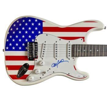 Willie Nelson Signed American Flag Graphics Stratocaster-Style Guitar (JSA): American flag graphics stratocaster-style guitar signed on the pickguard in blue felt tip marker by musician Willie Nelson. Measuring 39" x 17.5" 1.75" and in fine condition. Obtained in-person. Accom
