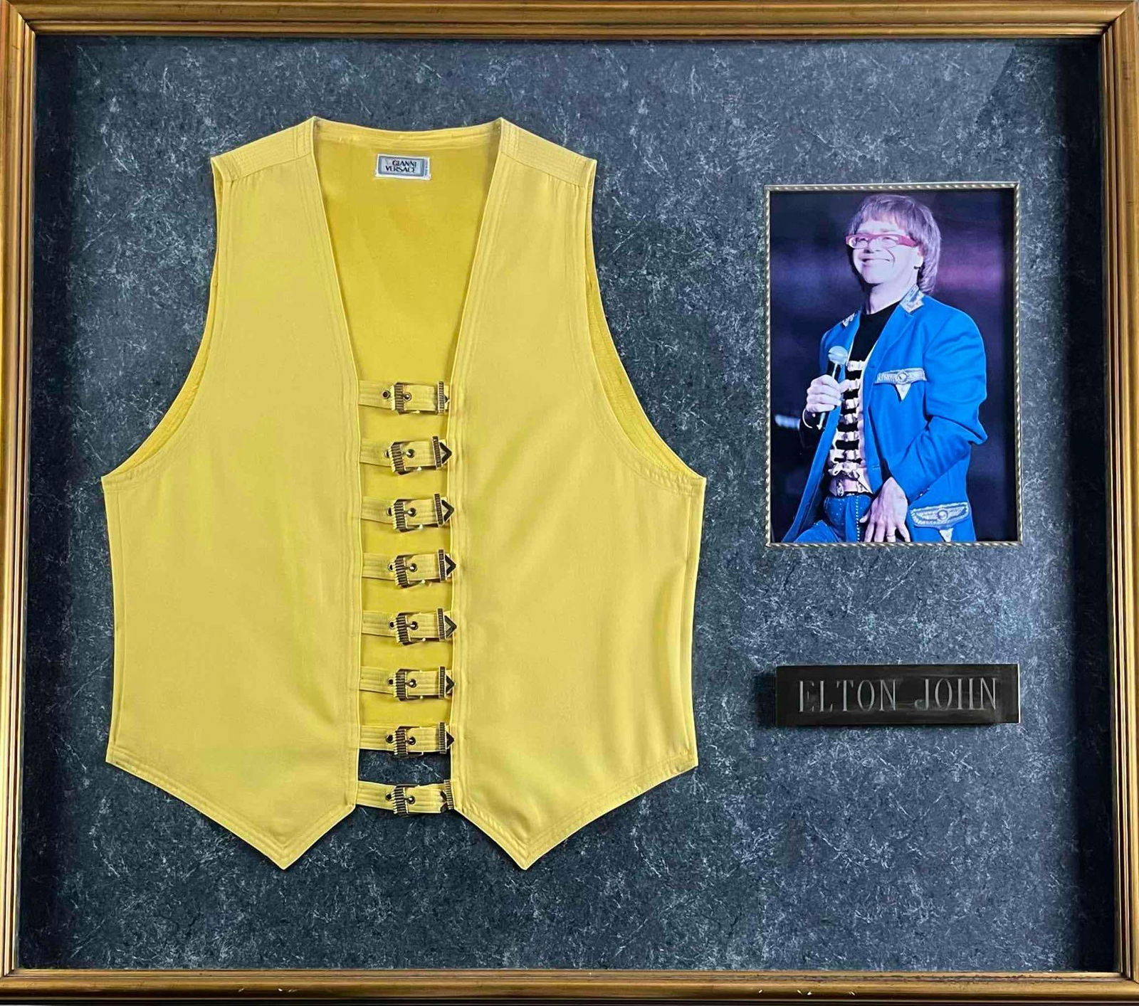 Elton John Stage-Worn Gianni Versace Yellow & Gold Vest Display (Provenance: Out of The Closet): Vibrant yellow and gold Gianni Versace vest personally owned and worn on stage by Elton John during his June 27, 1992 performance at Wembley Stadium in London, England. The vest, crafted in Versace