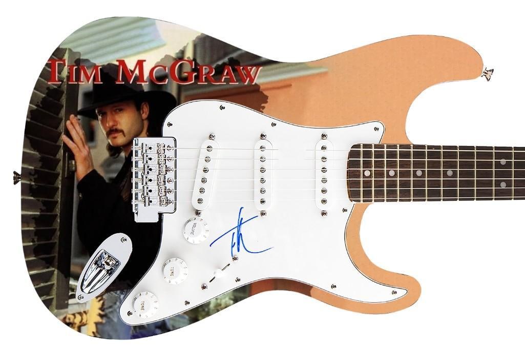 Tim McGraw Signed Graphics Fender Stratocaster Guitar (Roger Epperson/REAL Authentication): Tim McGraw graphics Fender Stratocaster guitar signed on the pickguard in blue felt tip marker by musician Tim McGraw. Measuring 39” x 12.75” x 1.75” and in fine condition. Acco