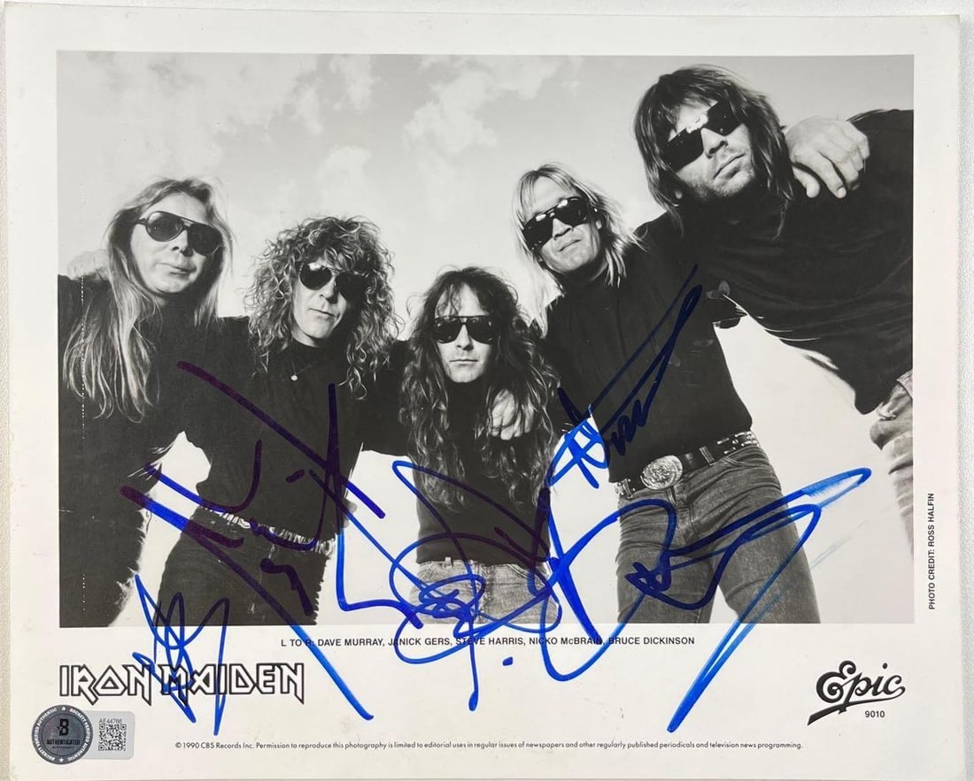 Iron Maiden Fully Group Signed 8" x 10" Promotional Photo (5 Sigs) (Beckett/BAS): Black-and-white 8" x 10" promotional photo published by Epic Records, signed in blue felt tip marker by Iron Maiden bandmembers Dave Murray, Janick Gers, Steve Harris, Nicko McBrain, and Bruce Di